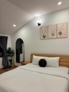 een slaapkamer met een groot wit bed met een kussen erop bij Quỳnh An Home in Da Lat