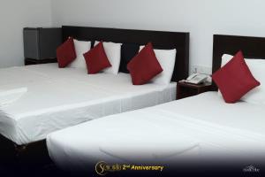 two beds with red pillows in a hotel room at Hotel Senondra Ampara in Ampara