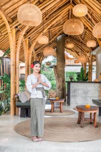 a woman standing in a room with her praying at Bamboo Asri Ubud in Ubud