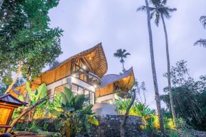 a house on a hill with palm trees at Bamboo Asri Ubud in Ubud