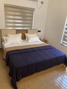 a bedroom with a large bed with a blue comforter at The Golden, Apartrooms in Trivandrum