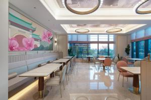 ein Restaurant mit Tischen, Stühlen und Blumen an der Wand in der Unterkunft Mercure Xiamen Science City in Xiamen
