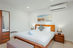 een witte slaapkamer met een bed en een spiegel bij Aruba Escape Spacious 5BR Villa for 12 by Bocobay in Oranjestad +55 foto's