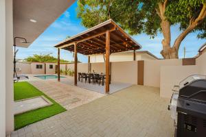 een paviljoen met een barbecue en een zwembad bij Aruba Escape Spacious 5BR Villa for 12 by Bocobay in Oranjestad