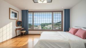 een slaapkamer met een groot bed en een groot raam bij Ganghwado Happyvilly Pension in Incheon