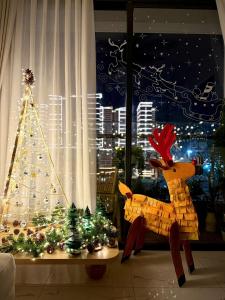 Ein Weihnachtsbaum und ein Rentier vor einem Fenster in der Unterkunft Jane's Cozy Home in Gò Công