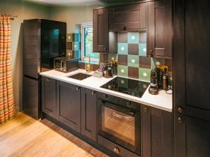 uma cozinha com armários castanhos escuros e um lavatório em The Twitcher - Uk50612 em Appletreewick