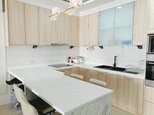 a kitchen with a white counter top and wooden cabinets at 3BR Pool Villa Beach Access Patumnak Hill in Pattaya South