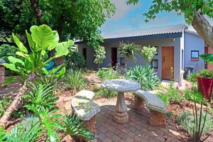 een tuin met een stenen bank en een huis bij The Chameleon Stay @107 in Centurion