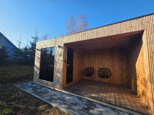 ein Gebäude mit zwei Stühlen auf einer Terrasse in der Unterkunft Domki Przystankowe 4 żywioły in Smerek