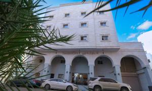 een gebouw met twee auto's ervoor geparkeerd bij فندق المغاربي للشقق الفندقية 3 in Al Madinah