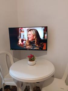 einen TV, der an einer Wand über einem weißen Tisch hängt in der Unterkunft La coquette de sidi bousaid in Sidi Bou Saïd