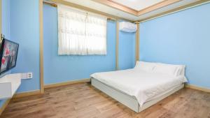 een blauwe slaapkamer met een bed en een blauwe muur bij Sokcho Dderak Pension in Sokcho