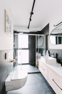 ein Badezimmer mit zwei Waschbecken, einer Toilette und einer Dusche in der Unterkunft Luma Central Viewpoint with Private Underground Parking in Târgu Mureș