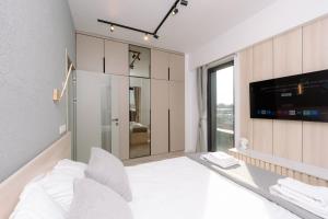ein Schlafzimmer mit einem weißen Bett und einem Fernseher in der Unterkunft Luma Central Viewpoint with Private Underground Parking in Târgu Mureș