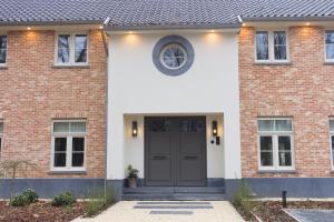 ein Backsteinhaus mit einer schwarzen Tür in der Unterkunft Bed and Breakfast L'Orée Du Bois in Wavre