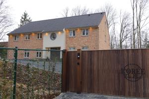 ein Haus mit einem Holztor und einem Zaun in der Unterkunft Bed and Breakfast L'Orée Du Bois in Wavre