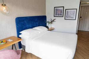 ein Schlafzimmer mit einem weißen Bett mit blauem Kopfteil in der Unterkunft Faranda Collection Cali, a member of Radisson Individuals in Cali