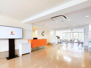 姫路市にあるコンフォートイン姫路夢前橋のスクリーンとテーブルと椅子のある空の部屋