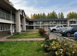 a building with cars parked in a parking lot at Quesnel Inn in Quesnel