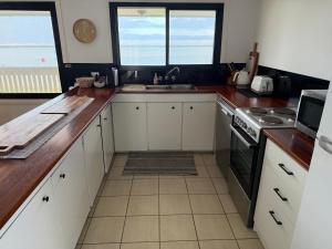a kitchen with white cabinets and a sink and two windows at Harrington Haven in Harrington +22 photos