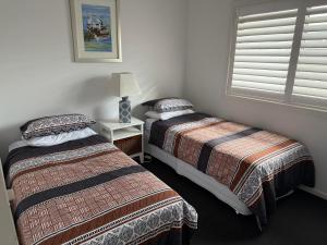 a bedroom with two beds and a lamp and a window at Harrington Haven in Harrington