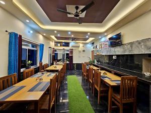 a restaurant with wooden tables and chairs and a ceiling fan at Geetanjali Palace Hotel & Restaurant in Rudraprayāg