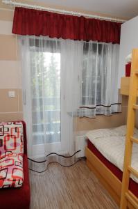a bedroom with a bed and a window with curtains at Zeleni Apartment Rogla in Zreče