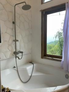ein Badezimmer mit Badewanne und Fenster in der Unterkunft Covehill Green Resort in Pelabuhan Ratu