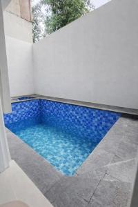 a swimming pool with blue tiles in a white wall at Kira Villa in Tlekung