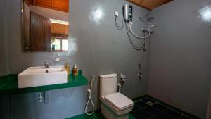 a bathroom with a white toilet and a sink at Chena Huts Eco Resort in Sigiriya
