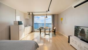 una camera da letto con tavolo e una cucina con vista sull'oceano di Yeosu Harushimpyo Pension a Yeosu
