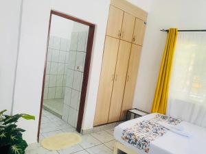 a bathroom with a shower and a bed and a mirror at Tash Studios in Diani Beach