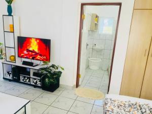 een woonkamer met een televisie en een badkamer bij Tash Studios in Diani Beach