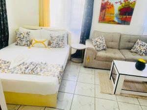 een kleine woonkamer met een bed en een bank bij Tash Studios in Diani Beach