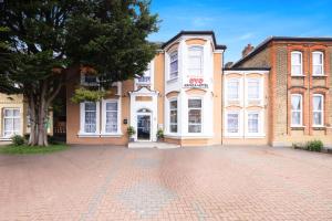 a large brick building with a tree in front of it at Arinza Hotel, London Ilford in Ilford
