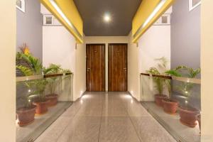 een gang met potplanten en houten deuren bij Hotel Girishankara in Indore +3 foto's