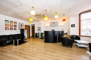 a living room with black furniture and a wooden floor at Arinza Hotel, London Ilford in Ilford