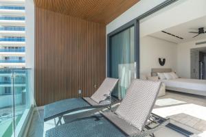 a balcony with two chairs and a bed in a room at Encantame Soleil New Resort 3rd Floor Studio in Playa Encanto