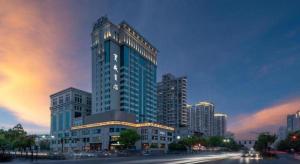 un gran edificio alto frente a una ciudad en Hangzhou Blossom Hotel, en Xiaoshan