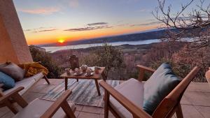 eine Terrasse mit einem Tisch und Stühlen sowie einem Sonnenuntergang in der Unterkunft Villa OVerdon in Aiguines