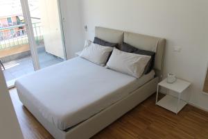 uma cama com lençóis brancos e almofadas num quarto em BiancAdele sul mare em Chiavari