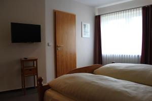 a hotel room with two beds and a television at Gästehaus Wacholderheide Garni in Eimke