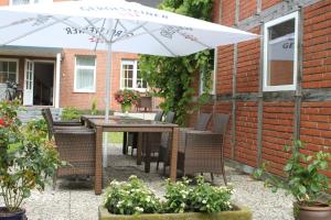 eine Terrasse mit einem Tisch, Stühlen und einem Sonnenschirm in der Unterkunft Gästehaus Wacholderheide Garni in Eimke