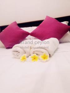 ein Bett mit lila Kissen und Handtüchern darauf in der Unterkunft Grand Ceylon Hotel & Apartment Hikkaduwa in Hikkaduwa