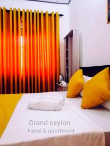 ein Schlafzimmer mit einem Bett mit gelben und orangefarbenen Kissen in der Unterkunft Grand Ceylon Hotel & Apartment Hikkaduwa in Hikkaduwa