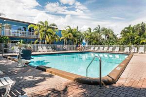 a swimming pool at a resort with chairs and a building at Rodeway Inn & Suites Fort Lauderdale Airport & Cruise Port in Fort Lauderdale