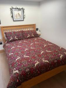 ein Bett mit einer roten Tagesdecke mit Pferdemotiven in der Unterkunft Tawny Lodge, Evesham Nr Cotswolds in Evesham