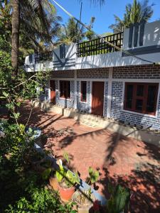 ein weißes Haus mit einer Backsteinterrasse davor in der Unterkunft Pearl farmstay in Kushālnagar