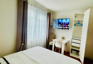 een slaapkamer met een bed, een tafel en een televisie bij Appartement F1 F2 in Drancy